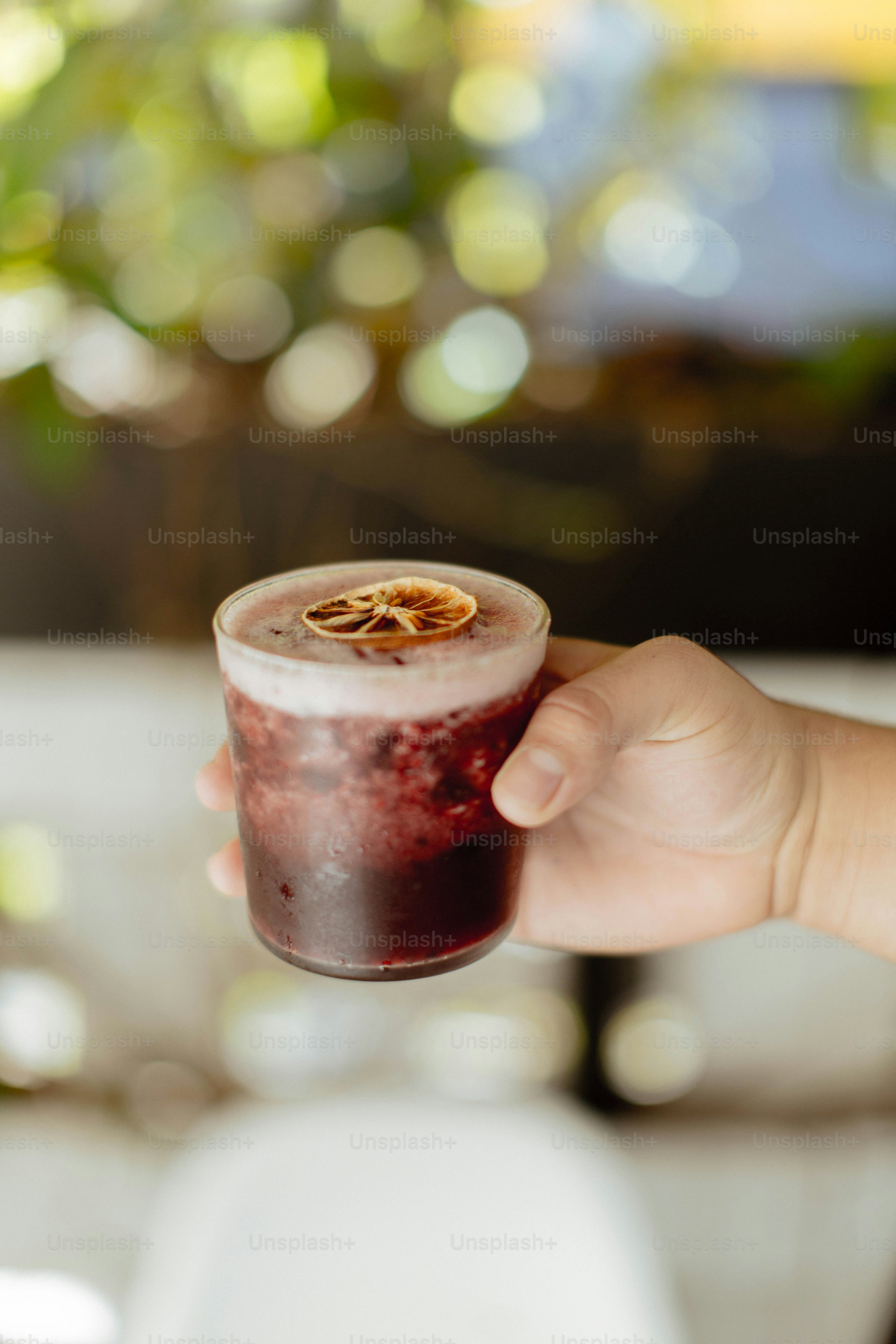 a hand holding a glass of liquid