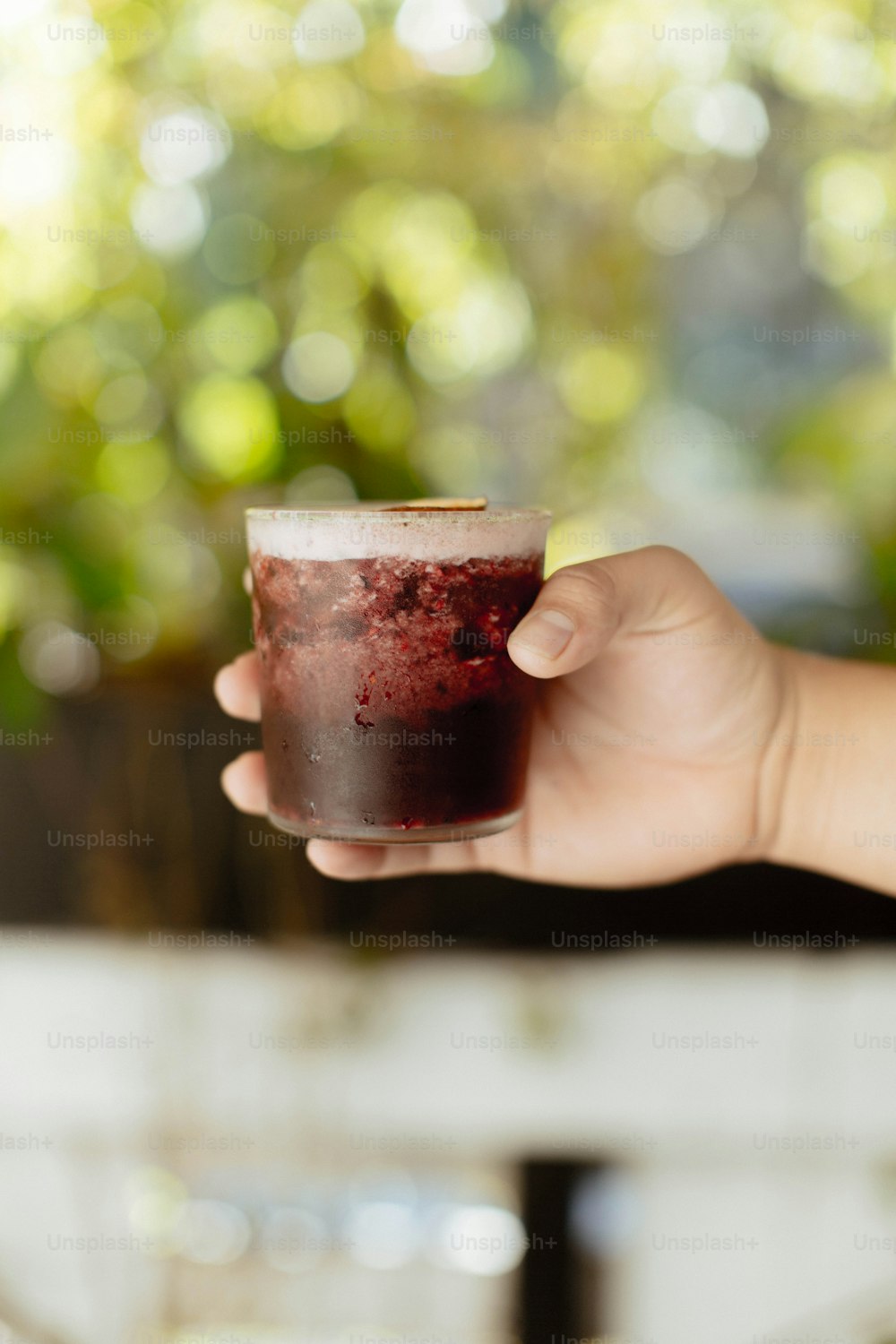 eine Person, die ein Glas Flüssigkeit in der Hand hält