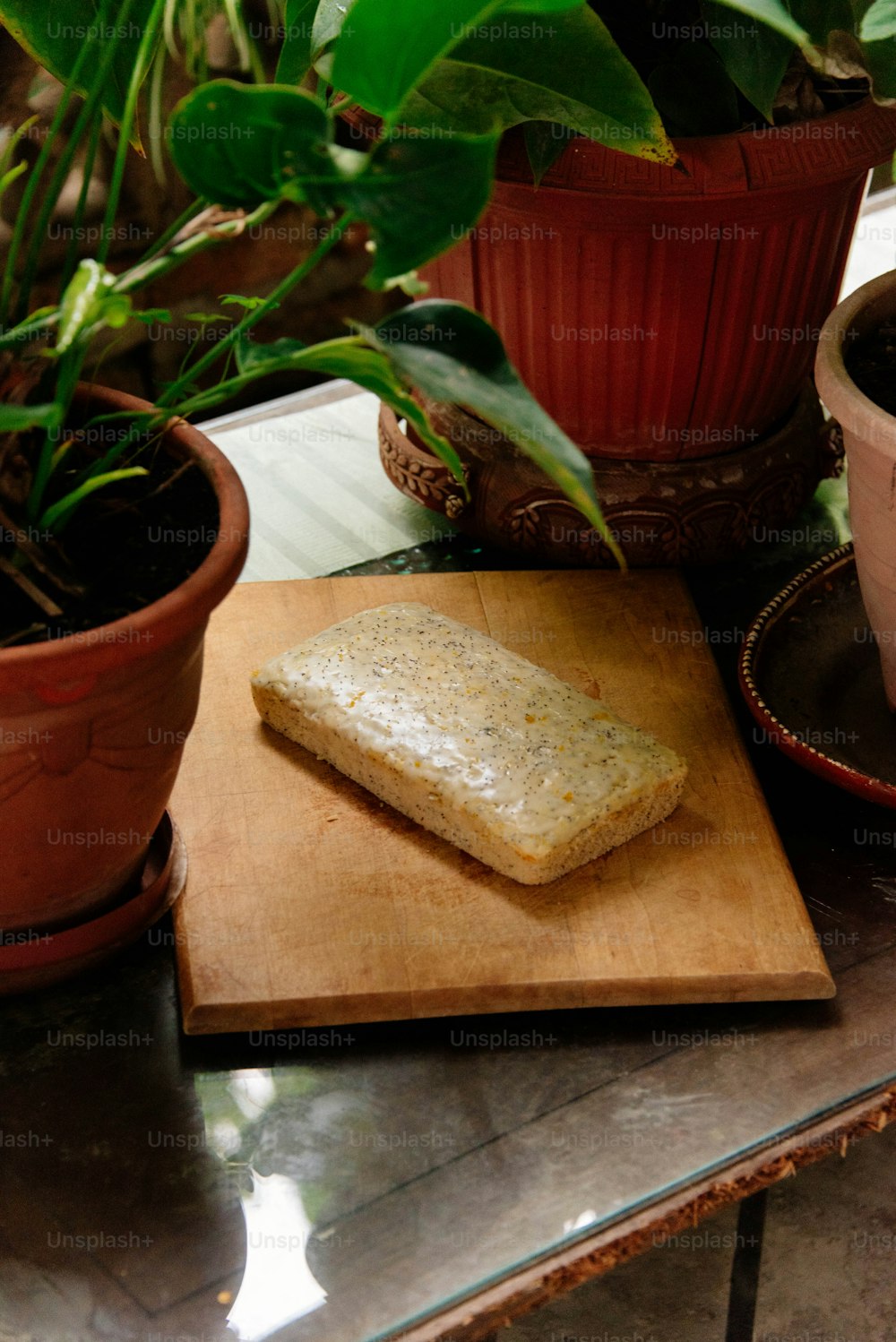 a loaf of bread on a cutting board next to potted plants