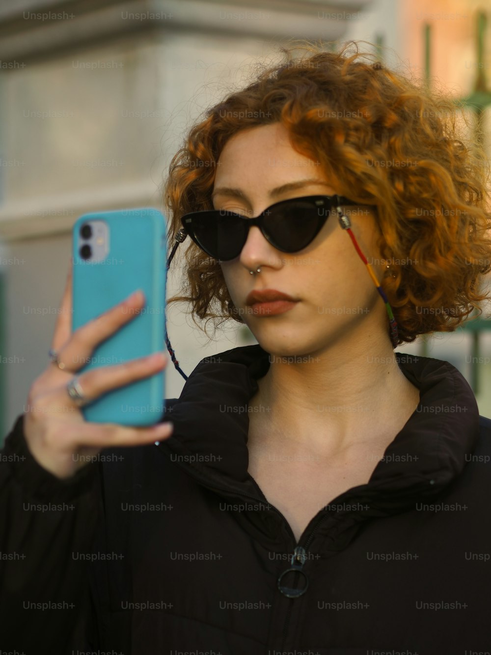 a woman with red hair and sunglasses holding a cell phone