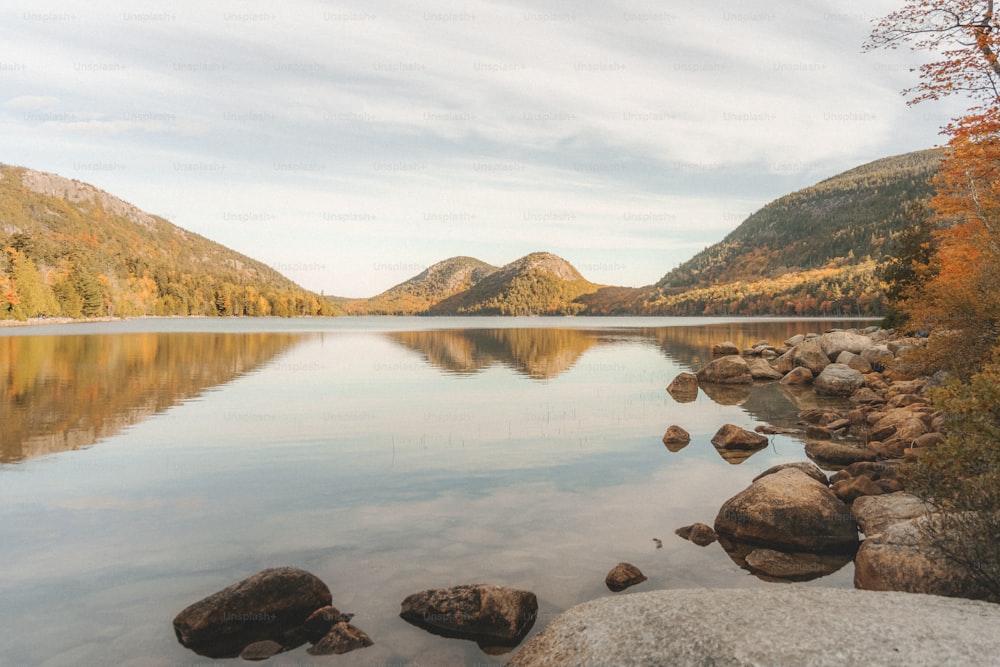 a lake with rocks and mountains in the background