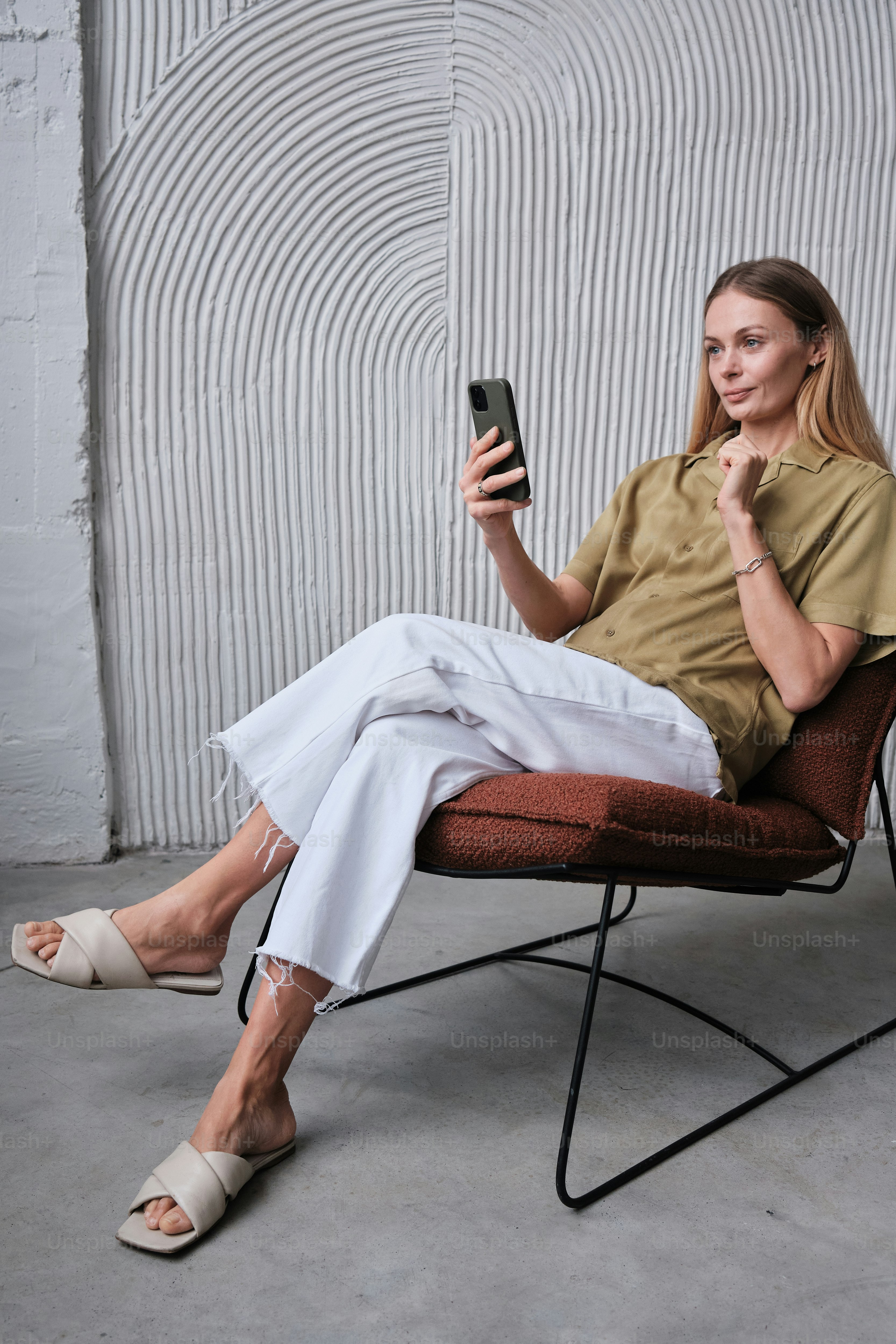 Portrait of a beautiful woman sitting in the armchair and taking a videocall