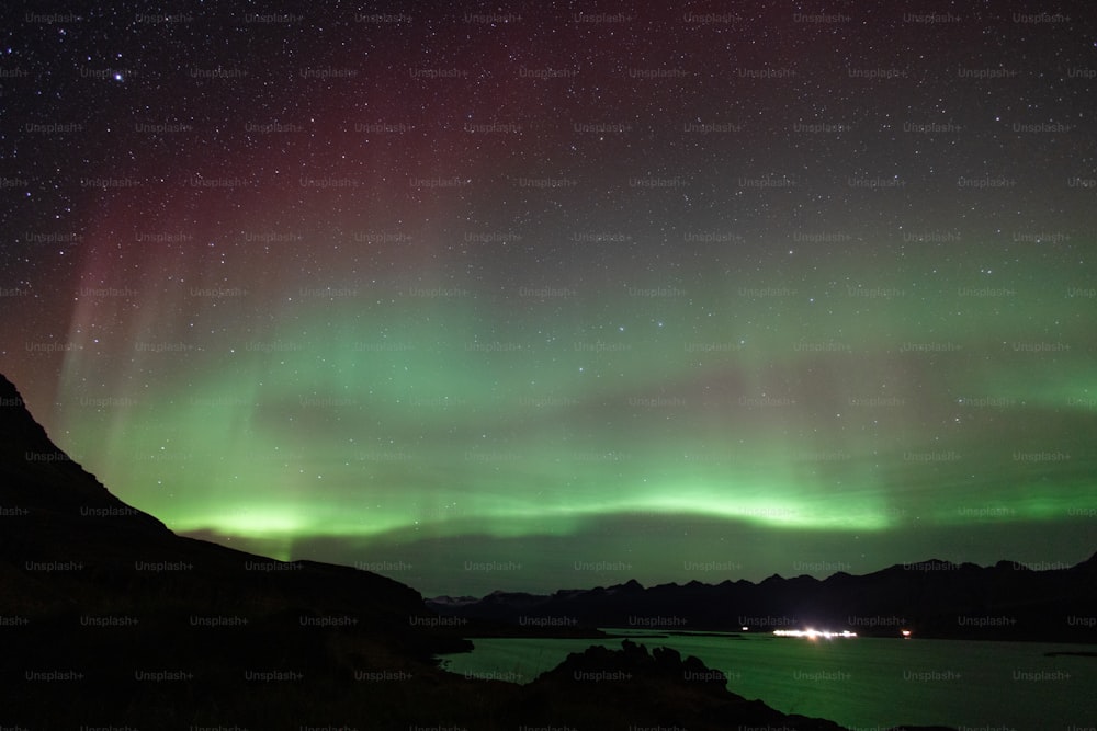 a green and purple sky over a lake and mountains