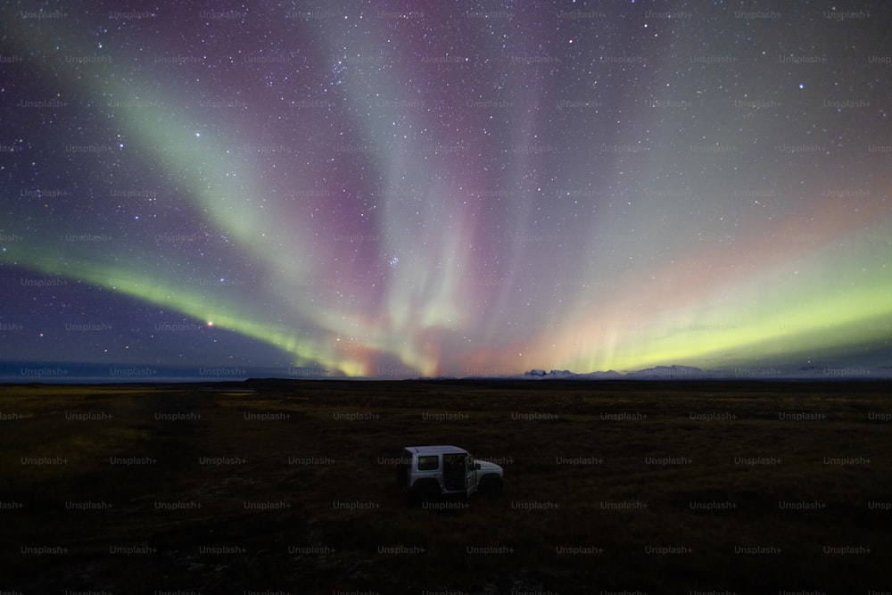 a car parked in a field with a bright light in the sky