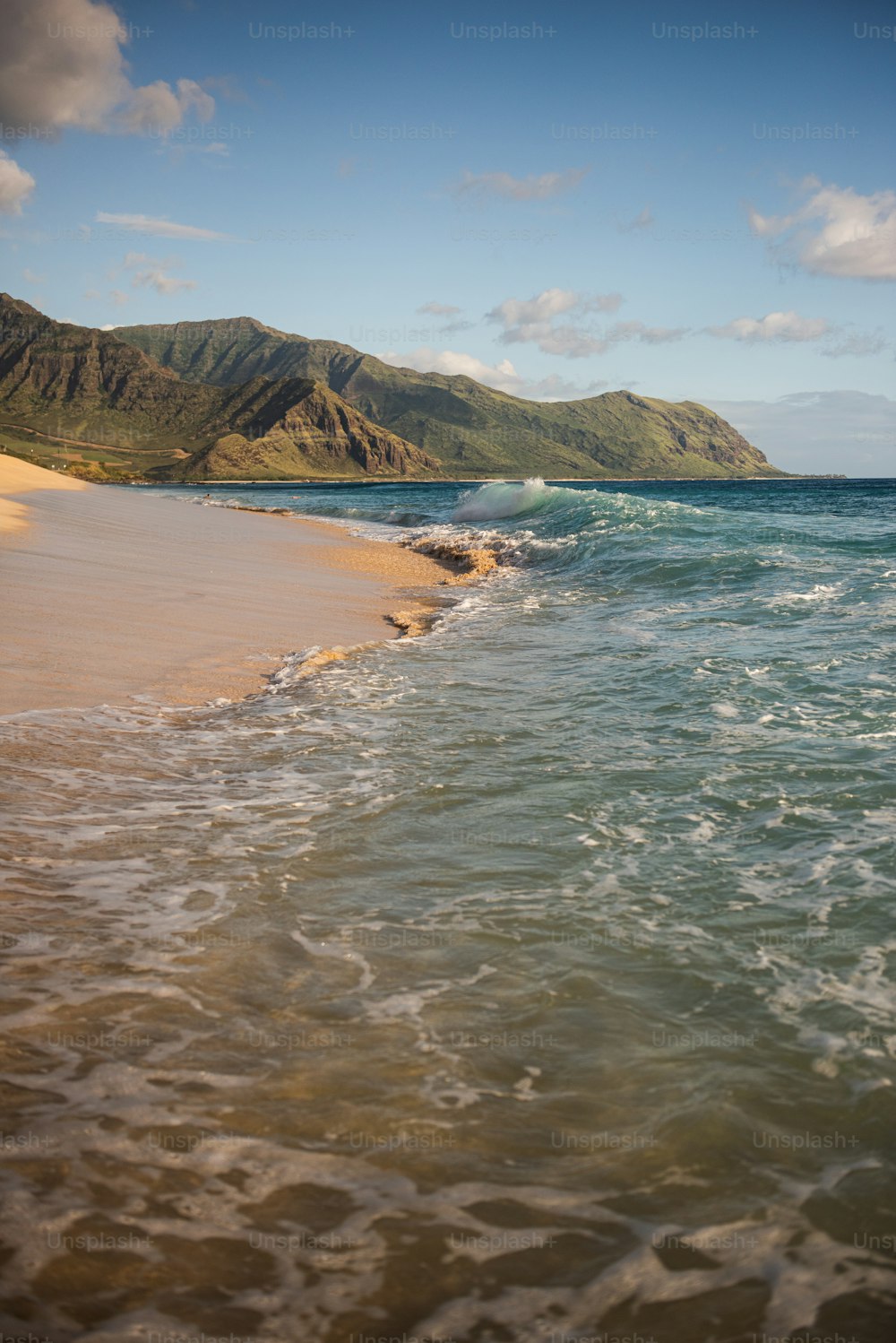 a beach with a body of water and mountains in the background