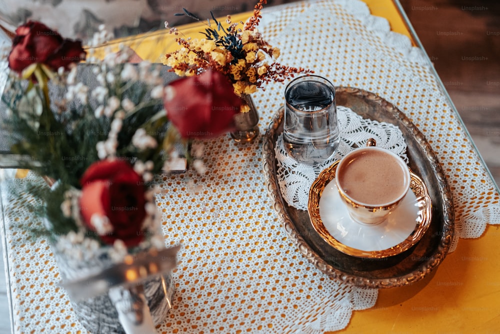 a cup of coffee and a bouquet of flowers on a table
