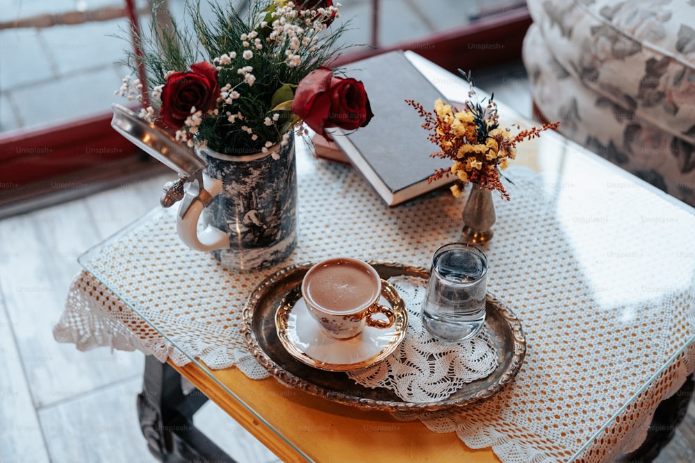 a vase with flowers and a cup of coffee on a table