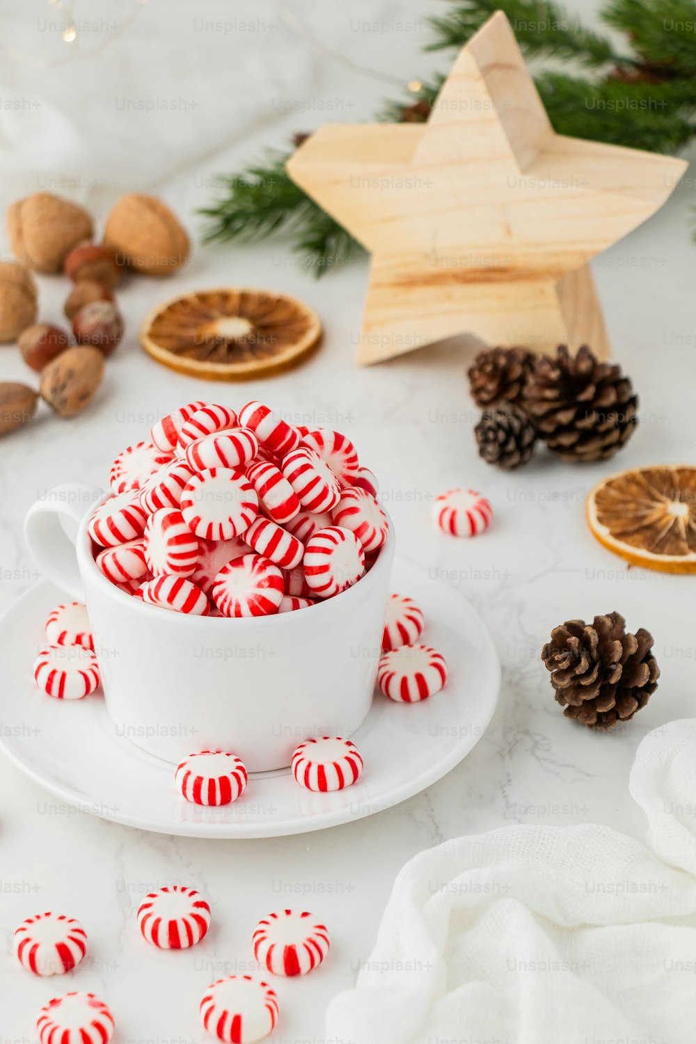 a cup of coffee with a gingerbread house and cookies on a white tablecloth