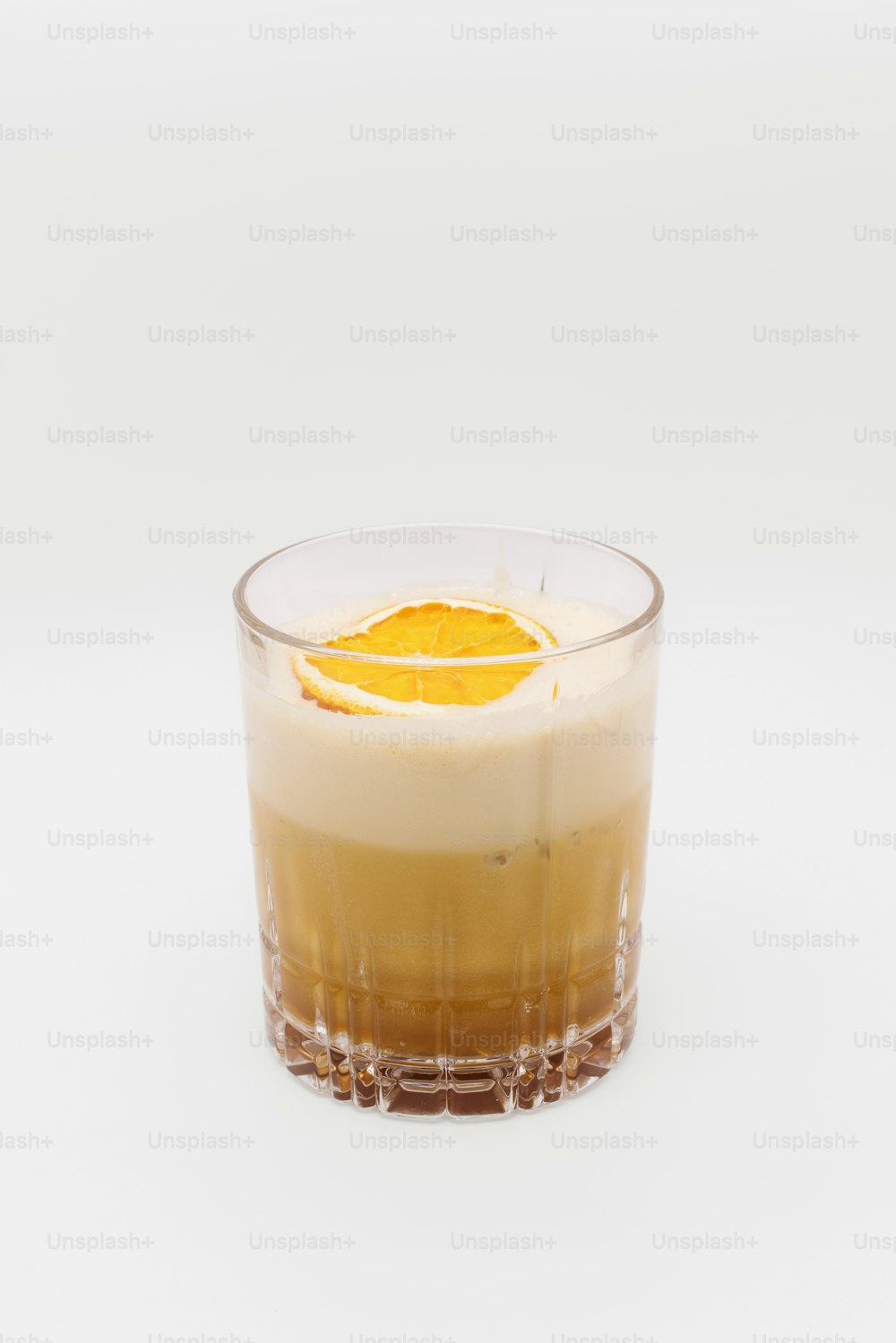 um copo de líquido com uma fatia de laranja por cima