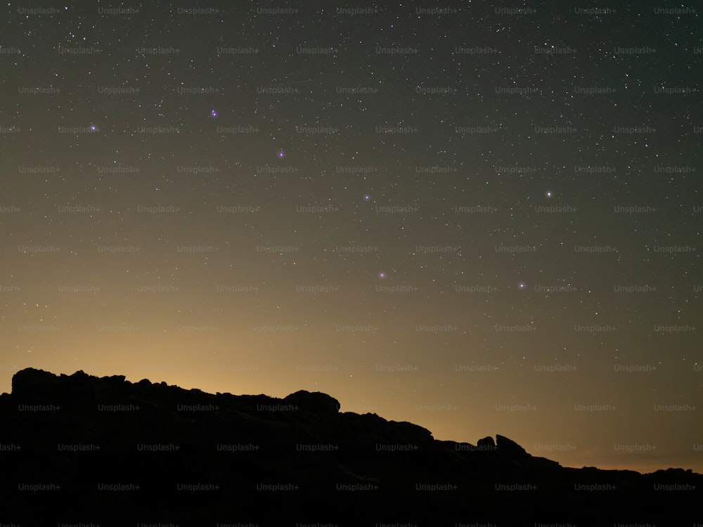 Un cielo nocturno estrellado sobre una cadena montañosa