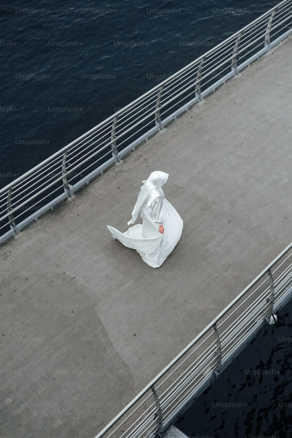 Una estatua de una persona sentada en un puente sobre el agua