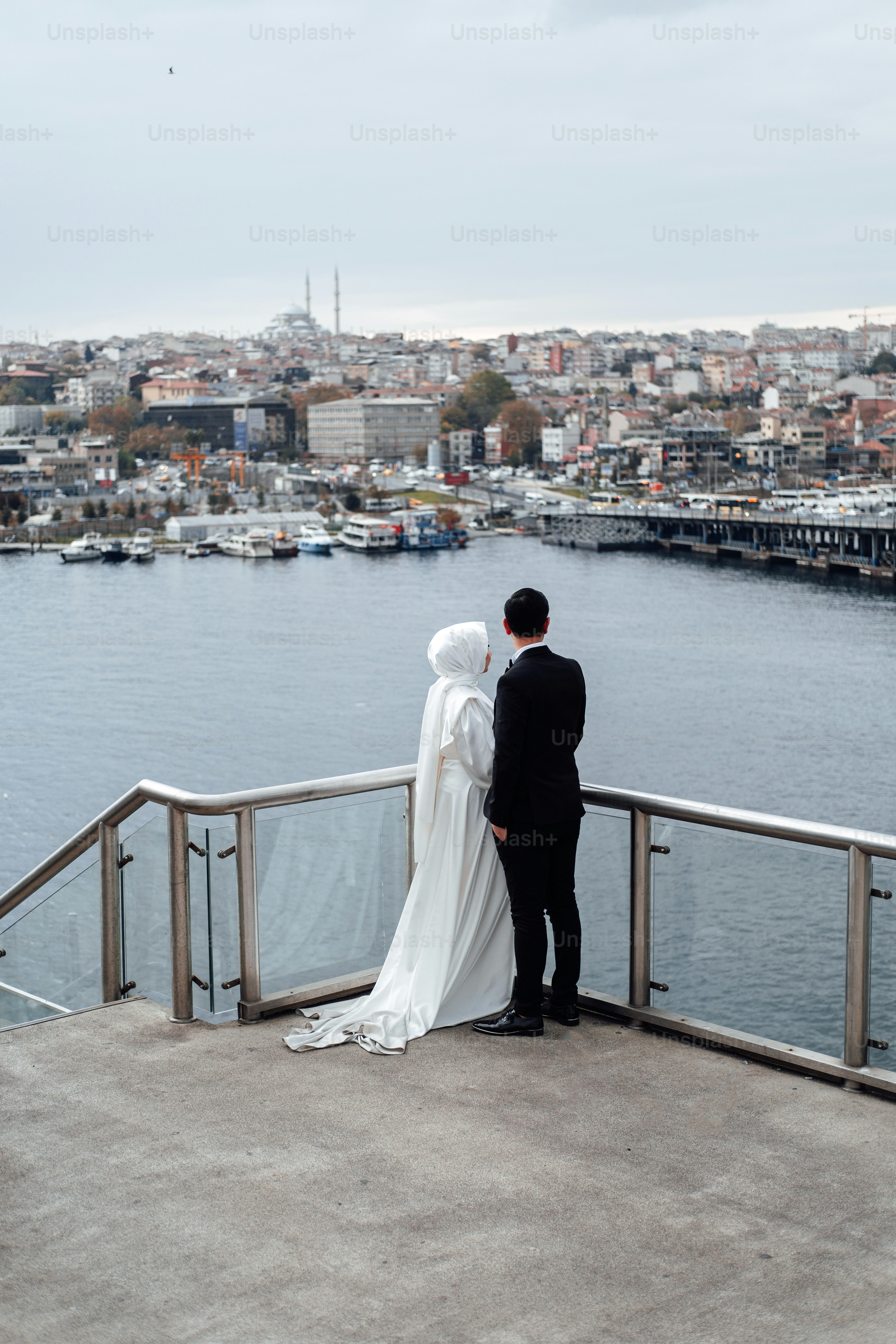 a man and woman standing on a bridge over a body of water