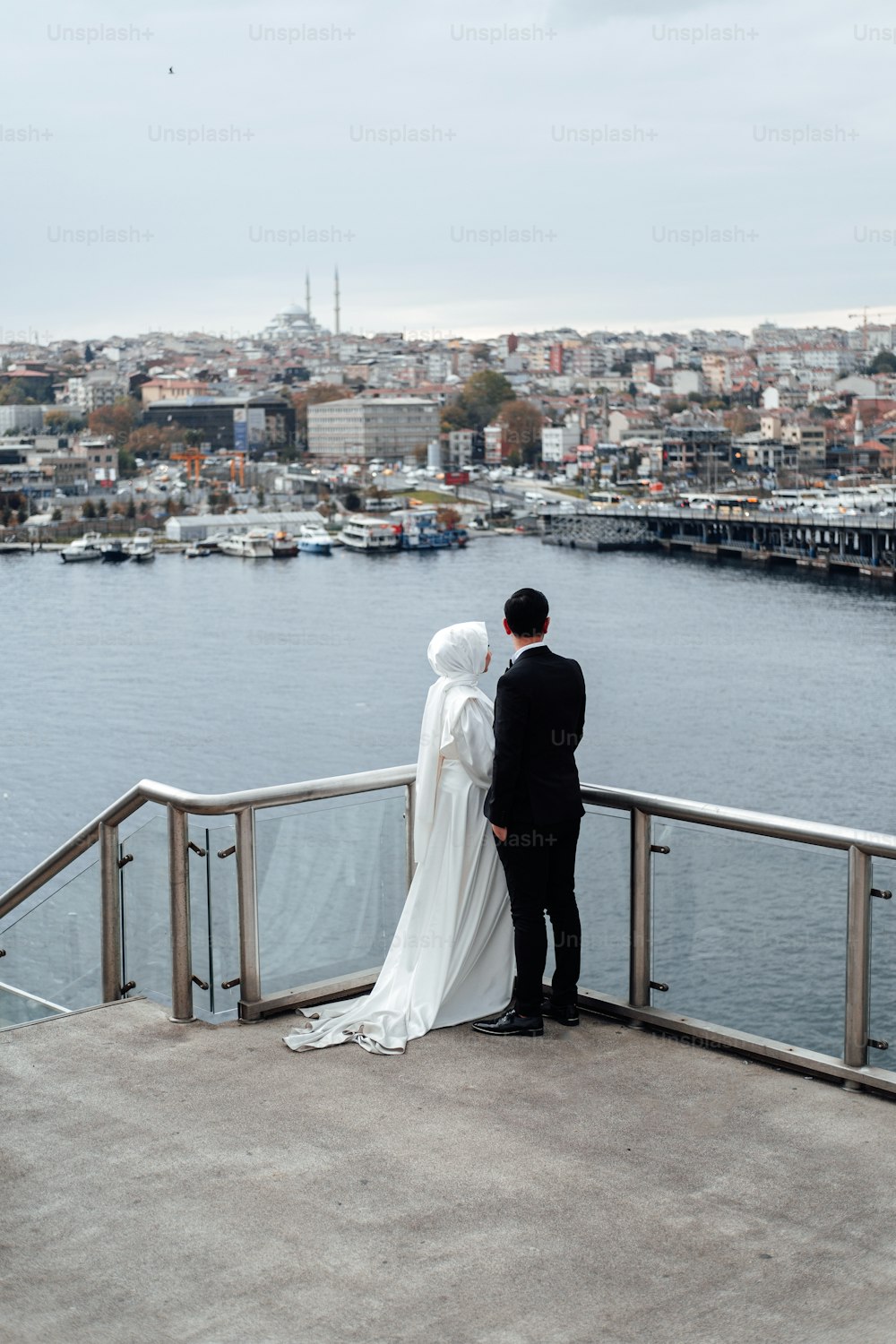 a man and woman standing on a bridge over a body of water