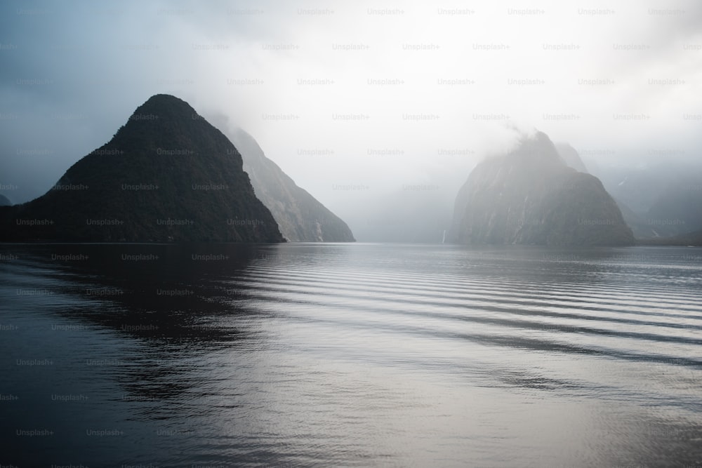 a body of water with a couple of large rocks in the distance