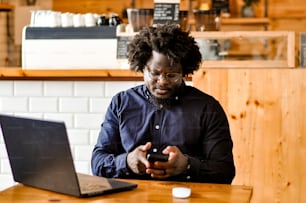 um homem sentado em uma mesa com um laptop e um telefone