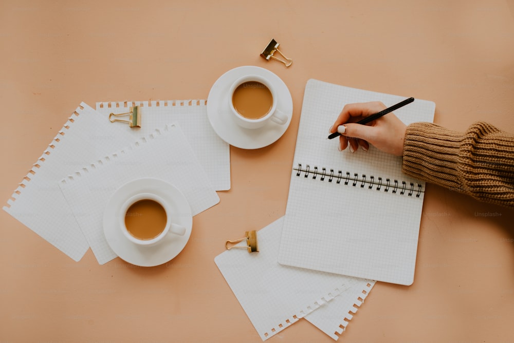 a hand holding a pen and paper next to a cup of coffee