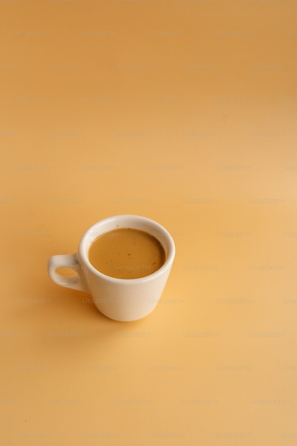 a white cup with a brown liquid