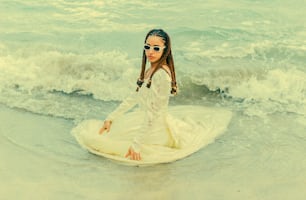 Un hombre con un vestido blanco sentado en una tabla de surf en el océano