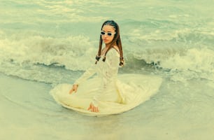 Un homme en robe blanche assis sur une planche de surf dans l’océan