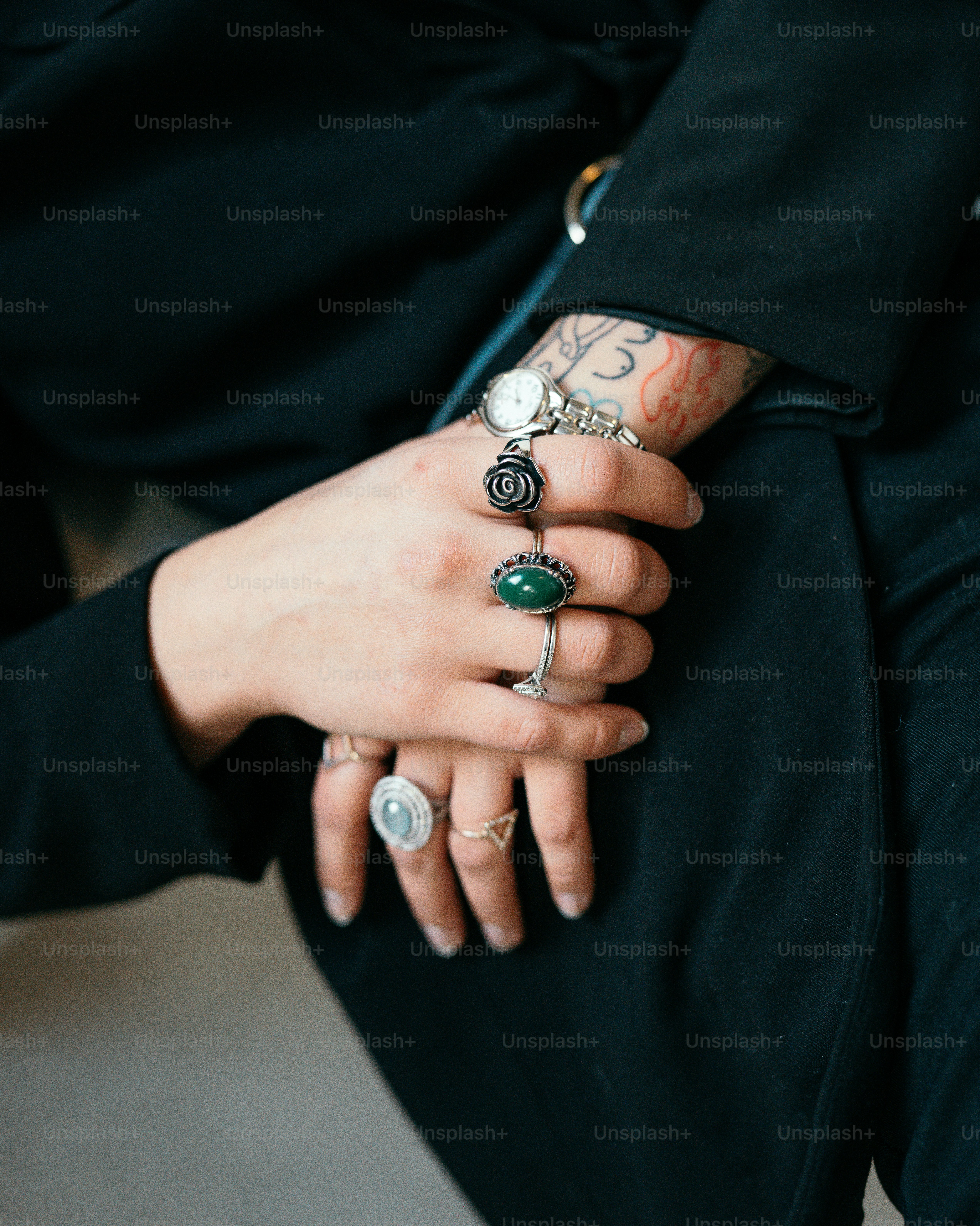 a person wearing a black jacket and a green ring