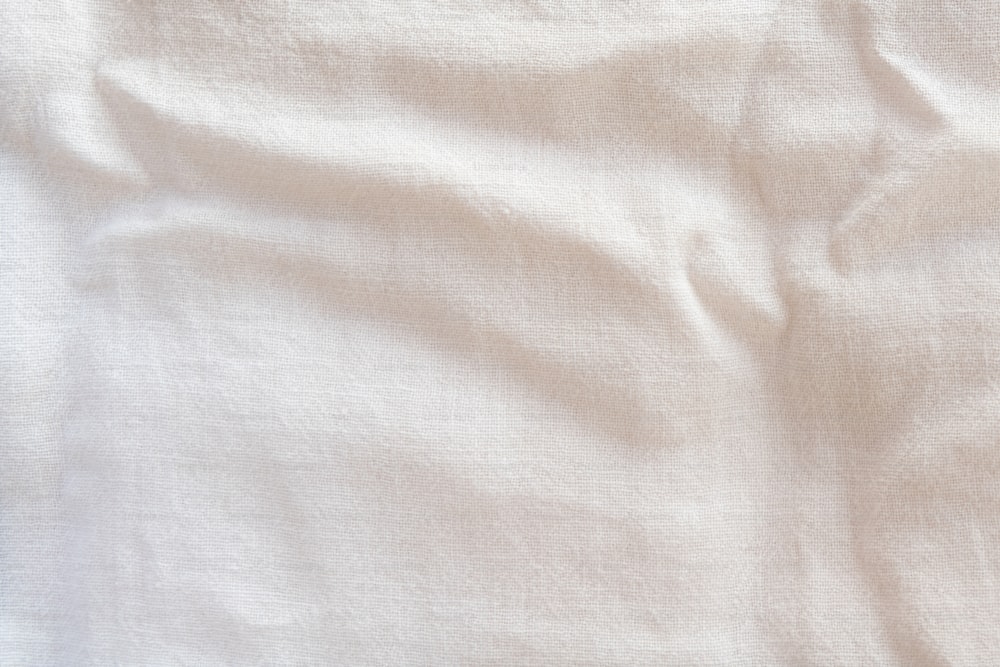 eine Nahaufnahme eines weißen Lakens auf einem Bett