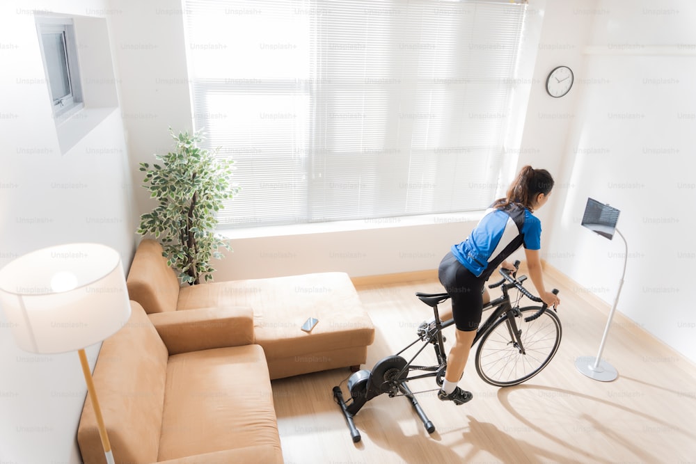 Asian woman cyclist. She is exercising in the home.By cycling on the trainer and play online bike games.