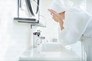 Asiatische Frau wäscht Gesicht im Badezimmer