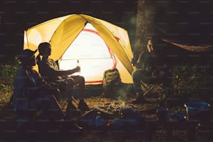 친구들은 밤에 숲에서 캠핑을하고 있습니다.