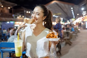 Os asiáticos estão comendo o jantar de comida de rua da Tailândia. Jantar na rua.
