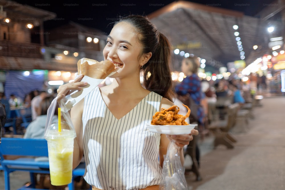 Os asiáticos estão comendo o jantar de comida de rua da Tailândia. Jantar na rua.