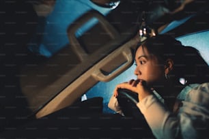 Une femme asiatique conduit seule la nuit. Il pleut. Elle est seule.