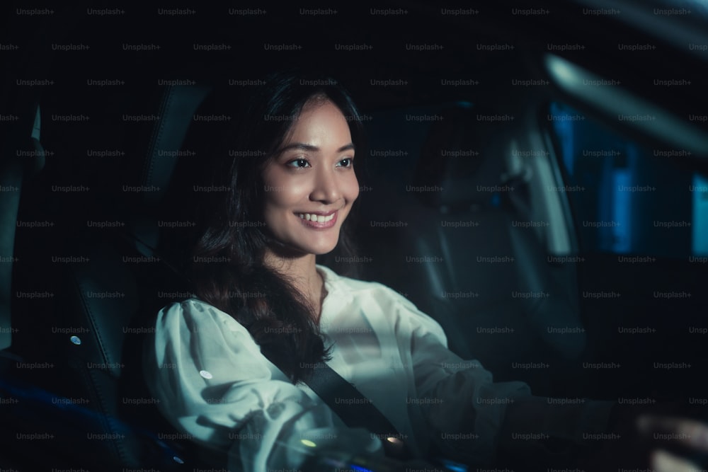 Mulher asiática está dirigindo sozinha à noite.