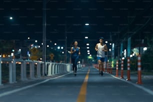 夜の街の通りをジョギングするアジア人夫婦