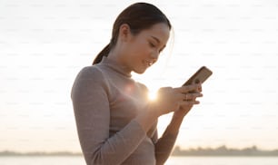 Asian woman using smart phone outdoors, she was smiling.