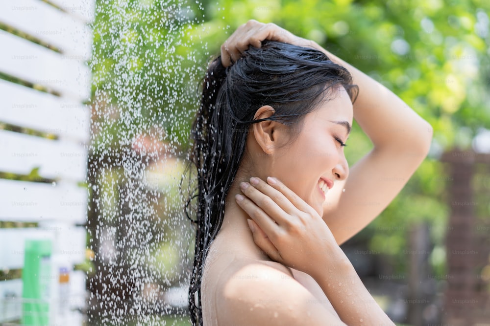 Donna asiatica, usa una doccia e lava i capelli fuori. Sta riposando al resort.