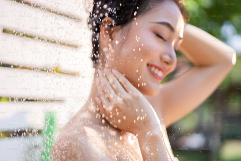 Donna asiatica, usa una doccia e lava i capelli fuori. Sta riposando al resort.concentrati sulla spalla