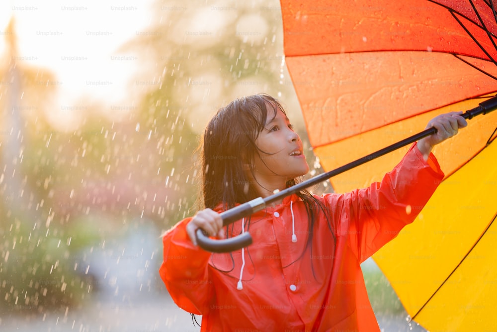 Menina asiática abre um guarda-chuva em um dia chuvoso.