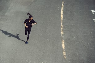 Femme de fitness elle court la route Elle regarde la vitesse de la montre-bracelet.