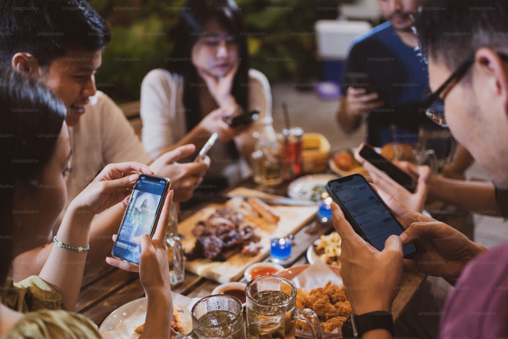 아시아 사람들은 테이블에서 휴대폰으로 파티와 채팅을하고 있습니다.