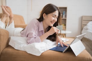 Asiatische Frau kauft online ein, sie benutzt eine Kreditkarte.