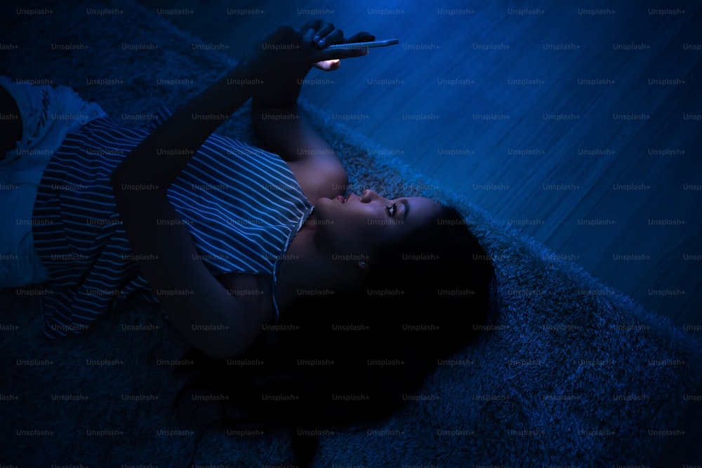 Une femme asiatique utilise son téléphone la nuit Elle discute et dort par terre.