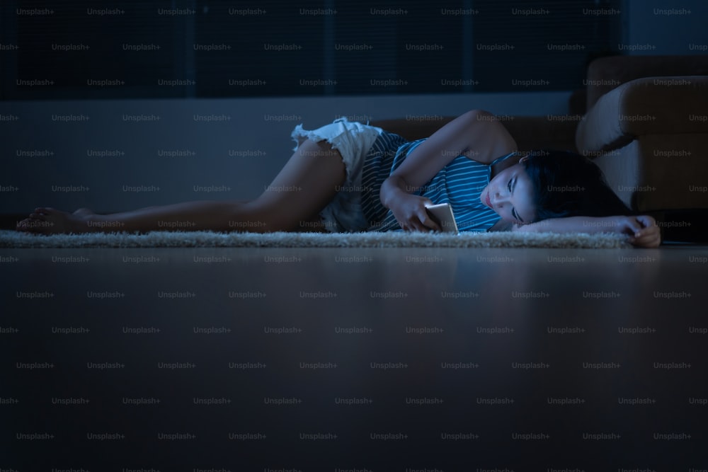 Asian woman uses her phone at night She sleeps on the floor