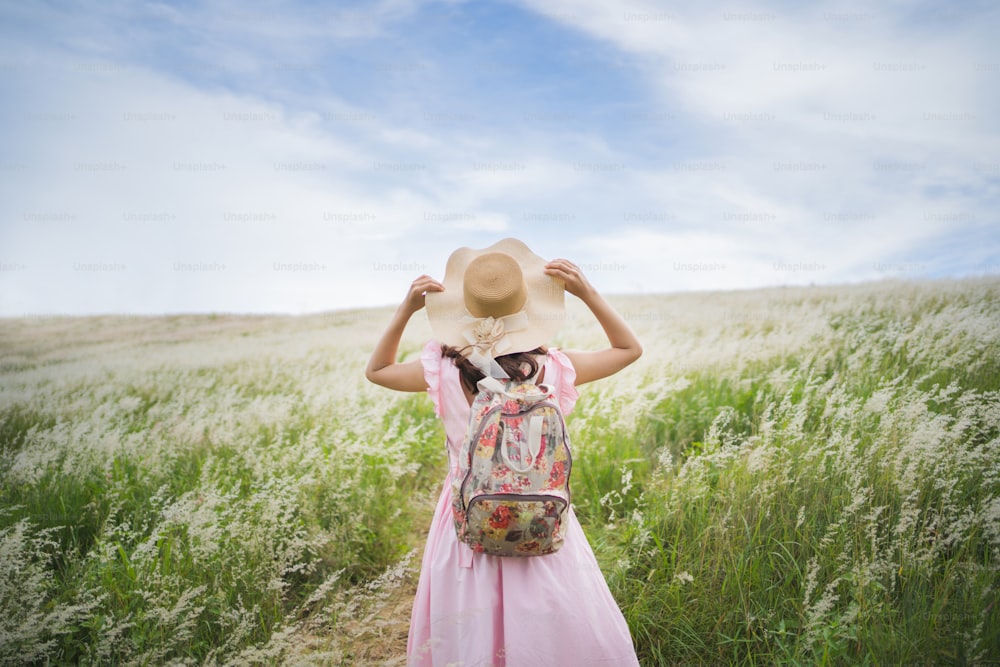 Female tourists Standing and holding a hat in the vast grassland