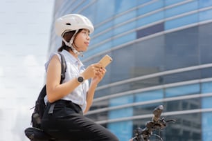 Mulheres trabalhadoras andam de bicicleta na cidade para trabalhar na hora do rush"nEla usa o telefone enquanto faz pausa.
