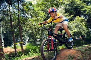 Il ragazzo asiatico si sta allenando per una felice mountain bike.