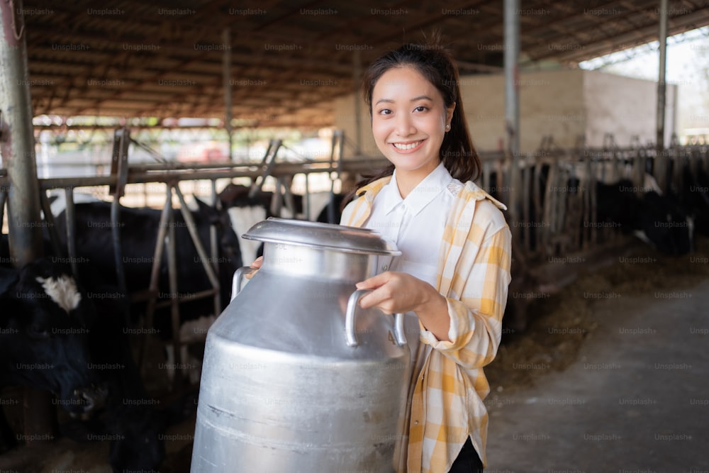 Retrato agricultor mulher asiática estão segurando um recipiente de leite em sua fazenda.