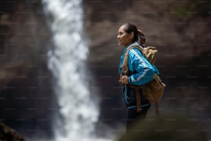 Asiatische Frau, sie tourt durch den Wasserfall
