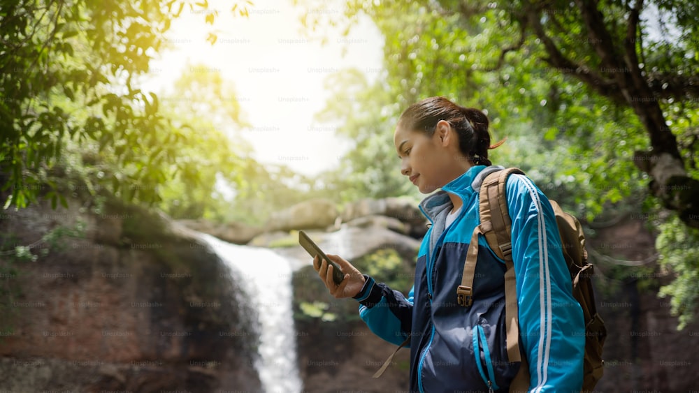 Donne asiatiche Usa il telefono durante un viaggio nella foresta e nella cascata.