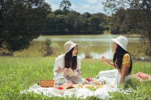 Amiche asiatiche, fanno picnic, mangiano al mattino, parlano felicemente.