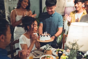 Grupo de amigos asiáticos Comemorando em uma festa de aniversário Ela está soprando velas